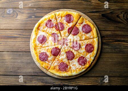 Köstliche frische Salami-Pizza auf Holztisch serviert. Draufsicht Stockfoto