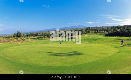 Golfer (Modell veröffentlicht) verlässt grün auf Mountain Course von Kona Country Club (Eigentum freigegeben) in Kailua Kona, Hawaii mit Hualalalai Berg. Stockfoto