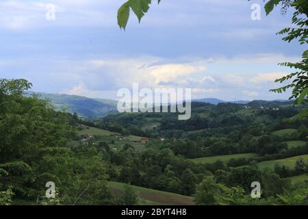 Dramatische Frühling Berglandschaft eines schönen grünen Wald, wo kleine Bergdörfer in der Ferne in ungewöhnlich ruhigen gelegen gesehen werden kann Stockfoto