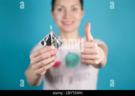 Ein junges Mädchen hält ein Kondom und ein Negativ aus Schwangerschaftstest in die Kamera Stockfoto