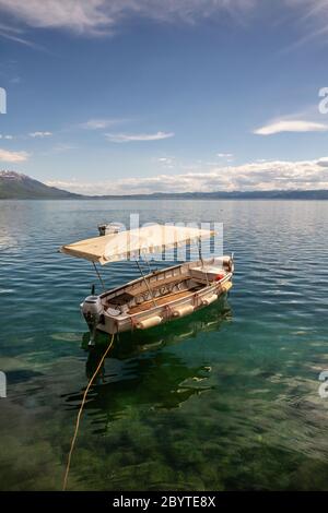 Ein leeres Motorboot, das an einem Sommertag an einem Felsen, klarem Wasser des Ohridsees, Stadt Ohrid, Republik Nordmazedonien (FYROM) festgemacht ist Stockfoto