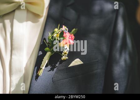 Nahaufnahme der Hochzeit boutonniere Blume auf Bräutigam Anzug. Bunte Pose am Revers der Jacke. Blau / weiß Kleid Kombination. Konzept für Hochzeitstag. Stockfoto
