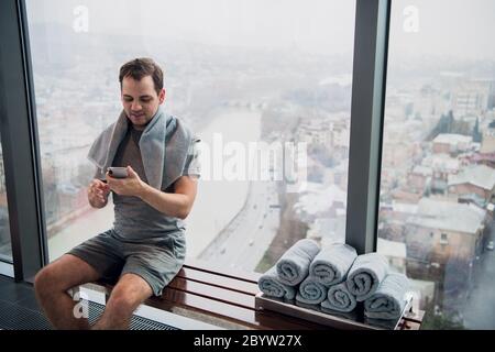 Schönen jungen Mann mit Handy ohne Übung Bruch in der Turnhalle Stockfoto