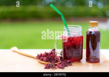 Kaltes Getränk Glas roselle Saft mit buntem Stroh in Holztisch Thai Kräutersaft und Erfrischung kaltes Getränk. Stockfoto