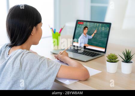 Asiatische Mädchen Student Videokonferenz E-Learning mit Lehrer auf Computer im Wohnzimmer zu Hause. Homeschooling und Fernunterricht, online, Bildung Stockfoto