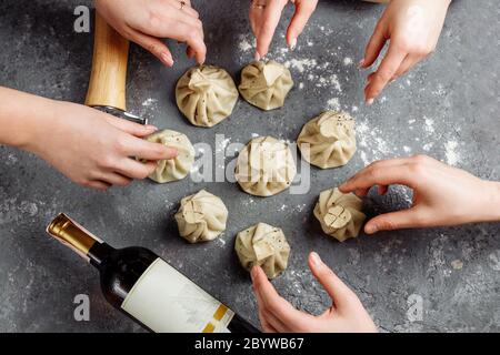 Khinkali, georgische Knödel, traditionelle georgische Küche. Hände von Menschen nehmen Khinkali von der Seite. Blauer Hintergrund, Kopierbereich. Stockfoto