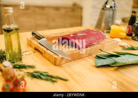 Rohes Fleisch Filet auf Holzbrett closeup, niemand. Nicht gegartem Fleisch, Gemüse, Gewürze und Gewürzen und Kräutern auf Arbeitsplatte, Küche Interieur auf Ba Stockfoto