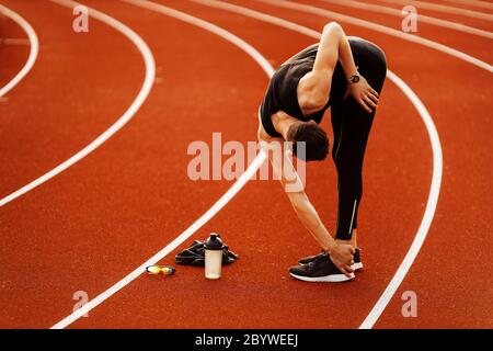 Junger schöner Mann beim Dehnen vor dem Laufen im Stadion Stockfoto