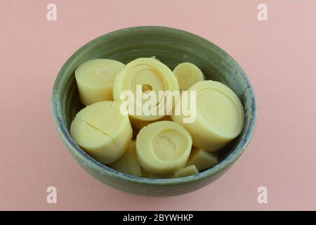 Dosenherzen aus Palmenscheiben in Keramikschale auf rosa Hintergrund Stockfoto