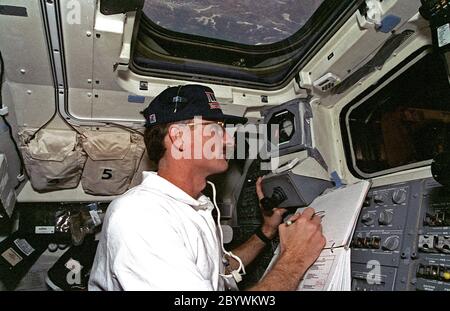 (11.-21. Februar 1997) --- Astronaut Joseph R. Tanner, ein halbes Weltraumspazierteam auf der Mission STS-82, das das Hubble Space Telescope (HST) in Betrieb nimmt, beobachtet die Extravehicular Activity (EVA) eines anderen Teams von Discovery's Achterdeck. Durch das Dachfenster von Discovery erscheinen Seen und ein Waldgebiet fast nah genug, um Tanner zu berühren Stockfoto