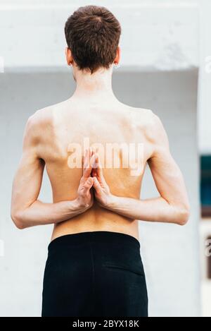Yoga-Haltung umgekehrtes Gebet oder Namast-Hände auf dem Rücken, die von einem jungen Mann im Freien durchgeführt werden. Stockfoto