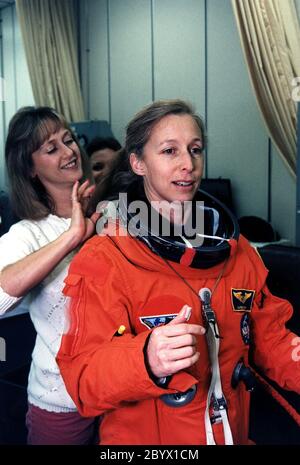 STS-81 Mission Specialist Marsha S. Ivins bekommt eine helfende Hand von einem Anzugtechniker, als sie sich darauf vorbereitet, den Helm ihres Anzugs/Einstiegsanzuges im Suitup-Raum des Operations and Checkout (O&C) Gebäudes anzuziehen. Sie ist die Veteran von drei Shuttle-Flügen und wurde Astronaut im Jahr 1984. Ivins wird unter anderem Foto- und Videoaufnahmen der russischen Raumstation mir durchführen und die Kidsat-Experimentkamera auf dem Achterdeck des Orbiters betreiben. Sie und fünf Besatzungsmitglieder werden in Kürze das O&C verlassen und sich auf den Launch Pad 39B begeben, wo das Space Shuttle Atlantis von du abheben wird Stockfoto