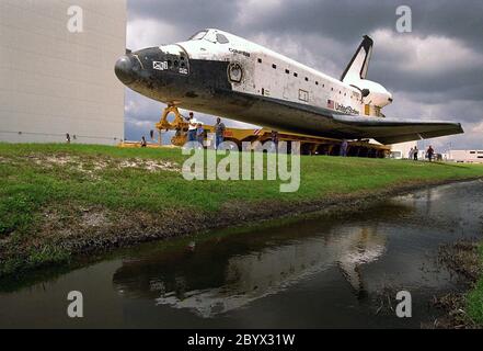 Das Space Shuttle Orbiter Columbia spiegelt sich in einem nahe gelegenen Teich wieder, während es vom 4. Juni von der Orbiter Processing Facility (OPF) 1 auf seinem Transporter zur Vorbereitung der STS-94-Mission zum Vehicle Assembly Building (VAB) überrollt wird. Sobald sie im VAB sind, wird Columbia mit seinen soliden Raketenverstärkern und einem externen Panzer hochgehisst. Columbia wurde am 8. April nach Abschluss der STS-83-Mission in die OPF verlegt. Die Mitarbeiter der KSC Payloads Processing begannen dann mit der Reservierung des Spacelab-Moduls Microgravity Science Laboratory-1 (MSL-1) im Nutzlastbereich des Orbiters für den STS-94 Miss Stockfoto