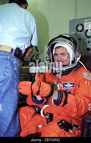 STS-94 Mission Commander James D. Halsell, Jr., zieht seinen linken Handschuh an, während er in seinem Start-/Einstiegsanzug im Operations and Checkout (O&C) Gebäude unterstützt wird. Halsell ist auf seinem vierten Raumflug, nachdem er als Kommandant von STS-83 und Pilot von STS-74 und STS-65 gedient hat. Er ist Oberstleutnant der Luftwaffe und ehemaliger SR-71 Blackbird Testpilot und hat Master-Abschlüsse in Management und Raumfahrtoperationen. Halsell wird für den Erfolg der Mission verantwortlich sein und Columbia während der Roten oder zweiten Schicht betreiben und unterhalten. Er wird auch mit einem helfen Stockfoto