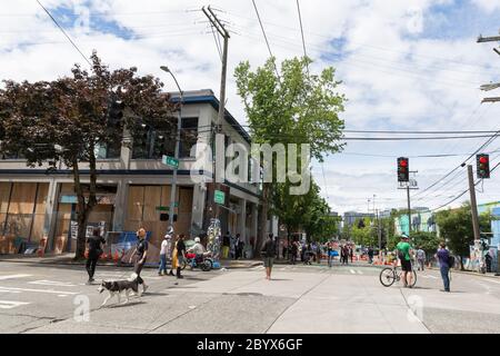 Die Menschen versammeln sich im East Precinct des verlassenen Polizeidezernats von Seattle im Capitol Hill in Seattle, Washington. Nach einer Woche großer Proteste und gelegentlicher gewalttätiger Auseinandersetzungen schloss das Polizeidezernat von Seattle am Montag, dem 8. Juni 2020, den Ostbezirk und entfernte wertvolle Gegenstände aus dem Gebäude. Stockfoto