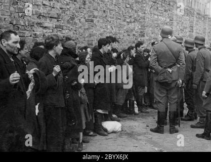 Warschauer Ghetto-Aufstand - Gefangene Juden werden nach Waffen gesucht und neben der Ghettomauer verhört, bevor sie auf den Umschlagplatz geschickt werden. 1943 Stockfoto