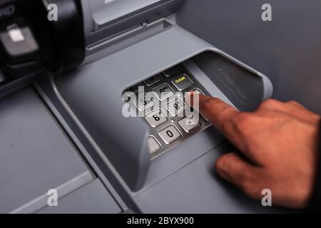 Nahaufnahme der männlichen Hand Eingabe der persönlichen Identifikationsnummer an einem Geldautomaten, um Bargeld abzuheben. Nahaufnahme. ATM-Transaktion. Weichzeichner. Tastatur. Stockfoto