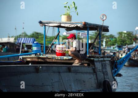 Ein Mann, der auf seinem Boot auf dem Hau-Fluss in Can Tho, Mekong Delta Region, Südvietnam einen Drink nimmt. Stockfoto