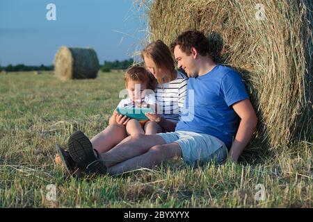 Dreier-Familie mit Unterlage auf dem Feld mit Heurollen Stockfoto