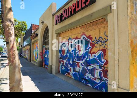 Leute, die draußen in einem Café vor gemalten Wandmalereien sitzen, protestieren gegen den Mord an George Floyd auf Sperrholzplatten, die Schaufenster am Lincoln Blvd, Santa Monica, Los Angeles, Kalifornien bedecken Stockfoto
