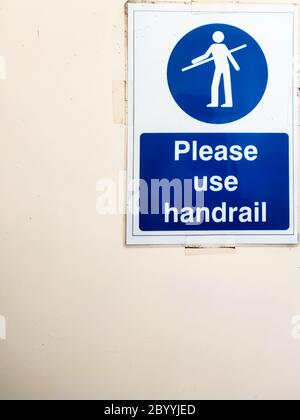 Bitte benutzen Sie ein Handlauf-Schild an der Wand neben der Rolltreppe. Stockfoto