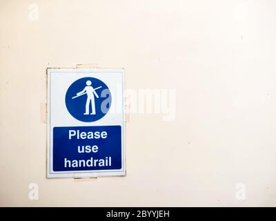 Bitte benutzen Sie ein Handlauf-Schild an der Wand neben der Rolltreppe. Stockfoto