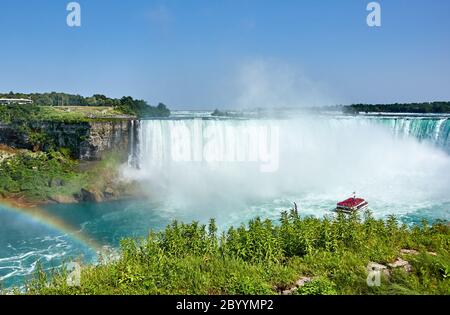 Niagara Falls, Kanada - 27. Juli 2019: Niagara Falls und Regenbogen im Sommer an einem klaren sonnigen Tag, Blick von der kanadischen Seite. Niagara Falls, Ontario, Cana Stockfoto