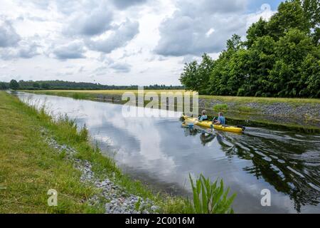 Zwei Kanufahrer sitzen im Kanu und paddeln auf einem Kanal Stockfoto