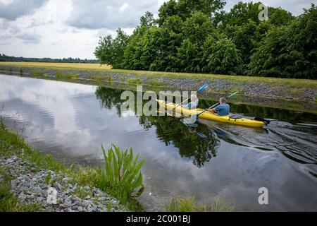 Zwei Kanufahrer sitzen im Kanu und paddeln auf einem Kanal Stockfoto