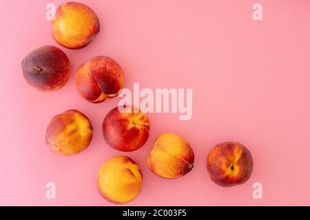 Pfirsiche aus nächster Nähe. Viele frische reife Bio-Früchte auf rosa Hintergrund, flache Lage, Kopierraum Stockfoto