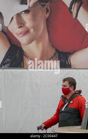Ein Passagier mit Gesichtsmaske geht während der Sperrung durch das COVID-19-Virus in einer Schlafmaske am fast leeren Frankfurter Flughafen vorbei. Weltweit ist die Luftverkehrsbranche stark von dem massiven Rückgang des Verkehrs betroffen. Stockfoto