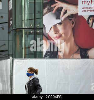 Ein Passagier mit Gesichtsmaske geht während der Sperrung durch das COVID-19-Virus in einer Schlafmaske am fast leeren Frankfurter Flughafen vorbei. Weltweit ist die Luftverkehrsbranche stark von dem massiven Rückgang des Verkehrs betroffen. Stockfoto
