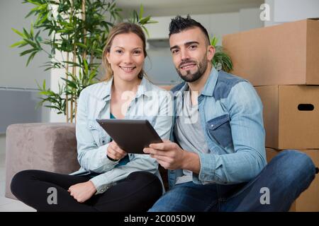 Glückliche neue Mieter sitzen in der Nähe von Kartons Stockfoto