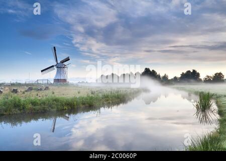 Windmühle und Fluss in nebligen Morgen Stockfoto