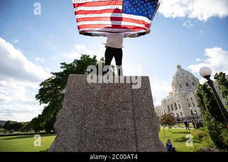 10. Juni 2020: Ein Aktivist hält eine Flagge hoch und steht dort, wo die Statue von Christoph Kolumbus wenige Minuten zuvor stand, bevor sie am 10. Juni 2020 in Saint Paul, Minnesota abgerissen wurde. (Bild: © Chris JuhnZUMA Wire) Stockfoto