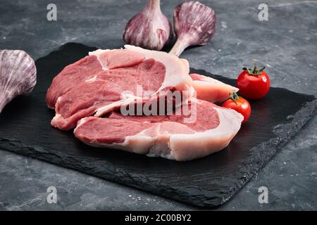 Schweinefleisch Steaks aus Filet, auf einem grauen Hintergrund Dekor Gemüse. Frisches Fleisch zum Kochen Steaks, Fotos für Lebensmittelgeschäfte. Kopien des Raumes. Stockfoto