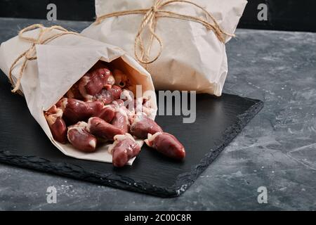 Rohe Hühnerherzen in ökologischer Verpackung verpackt. Rohes Hühnerfleisch auf grauem Zementgrund. Kopierplatz, Produktlieferung Stockfoto