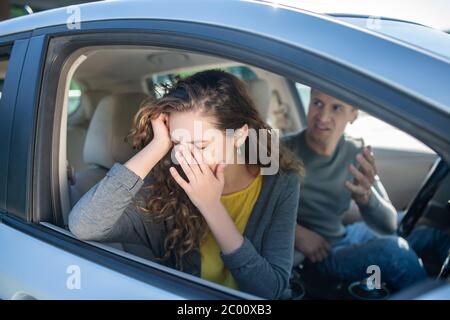 Weinende Frau und wütender Mann, der in einem Auto sitzt Stockfoto