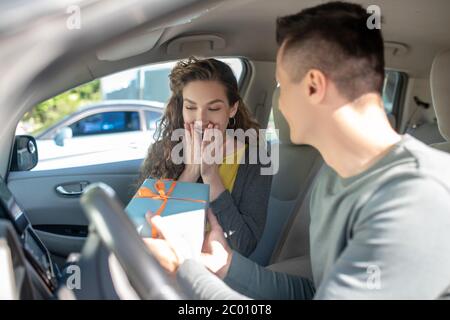 Freudig überrascht Frau und Mann mit Box im Auto Stockfoto