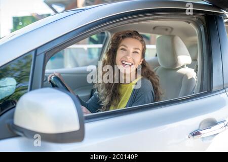 Lächelnde junge Erwachsene Frau sitzt in einem Auto. Stockfoto