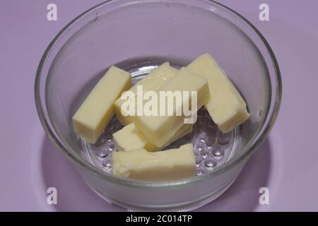 Butterstücke in Glasschale isoliert auf schwarzem Hintergrund Stockfoto