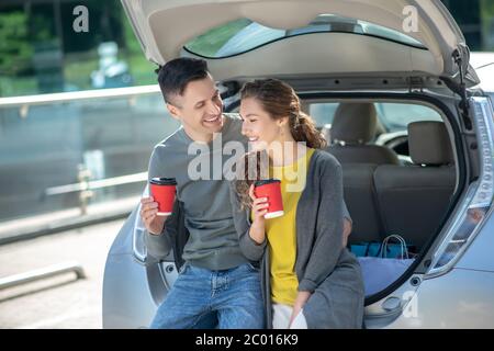 Mann und Frau beim Kaffee in der Nähe seines Autos. Stockfoto