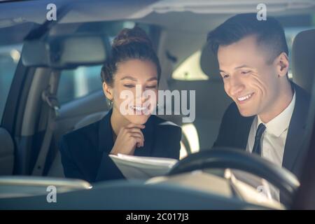 Junge erfolgreiche Frau und Mann Überprüfung Dokumente im Auto Stockfoto