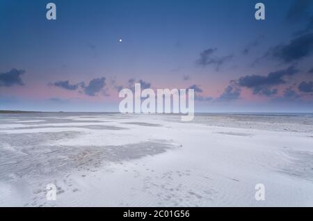 Vollmond und Sonnenaufgangshimmel über dem Sandstrand Stockfoto