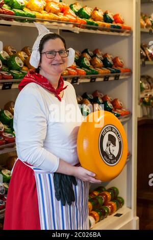 Ein Verkäufer in traditionellen holländischen Kleid posiert mit einer Runde Käse, Henri willig Cheeshop, Markt, Delft, Südholland, Niederlande Stockfoto