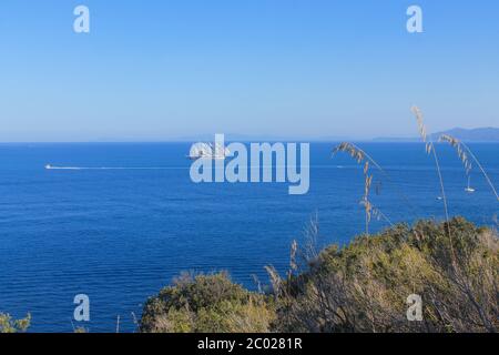 Blick auf das Tirrenische Meer mit Booten und Horizont mit Felsen und Vegetation im Vordergrund. Stockfoto
