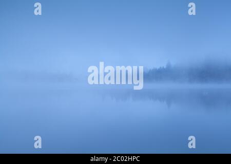 Dichter Nebel über dem See in den Alpen Stockfoto