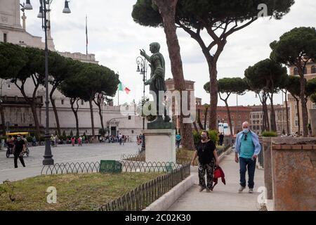 Menschen mit Schutzmaske gehen am 02. Juni 2020 entlang der Via dei Fori Imperiali im Zentrum Roms, als Italien beginnt, seine Sperre zu lockern, während das Land die Ausbreitung der COVID-19-Infektion, die durch das neuartige Coronavirus verursacht wird, eindämmen will. Stockfoto