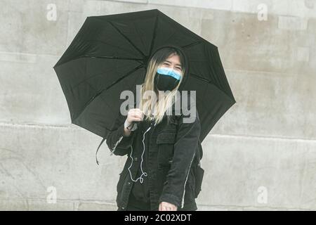 WESTMINSTER LONDON, GROSSBRITANNIEN. 11 Juni 2020. Fußgänger, die Schutzmaske tragen, schützen sich an einem regnerischen Tag in London unter einem Regenschirm auf dem Trafalgar Square. Kredit: amer Ghazzal/Alamy Live News Stockfoto