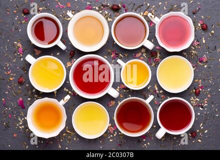 Auswahl an Teetassen auf dunklem, steinernem Hintergrund, Draufsicht Stockfoto